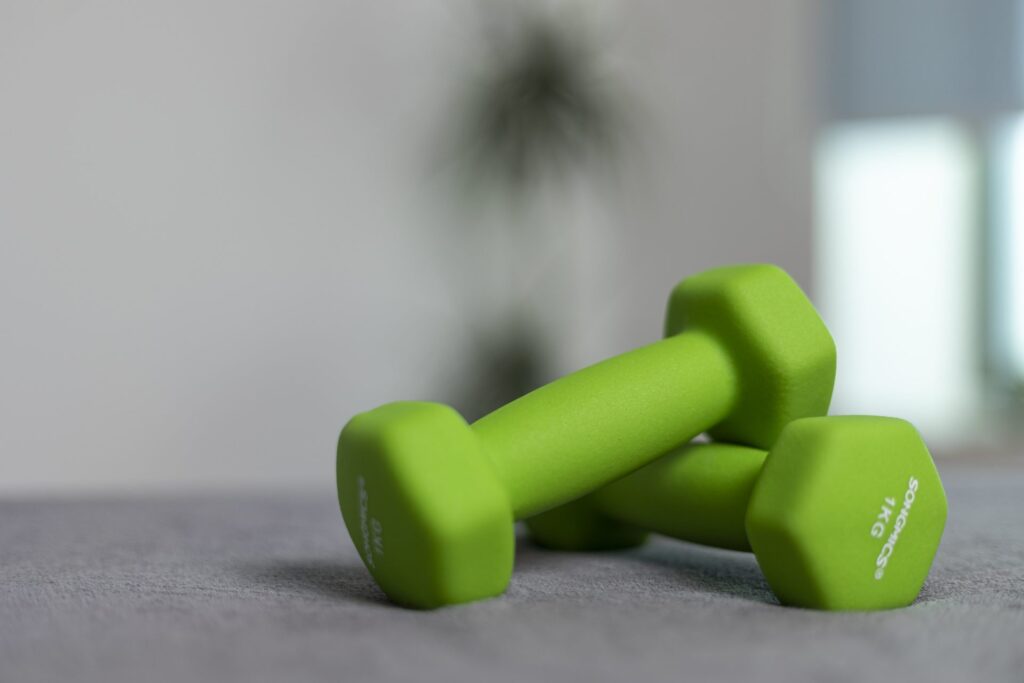 Zwei grüne 1-Kilogramm-Kurzhanteln liegen nebeneinander auf einer weichen Unterlage